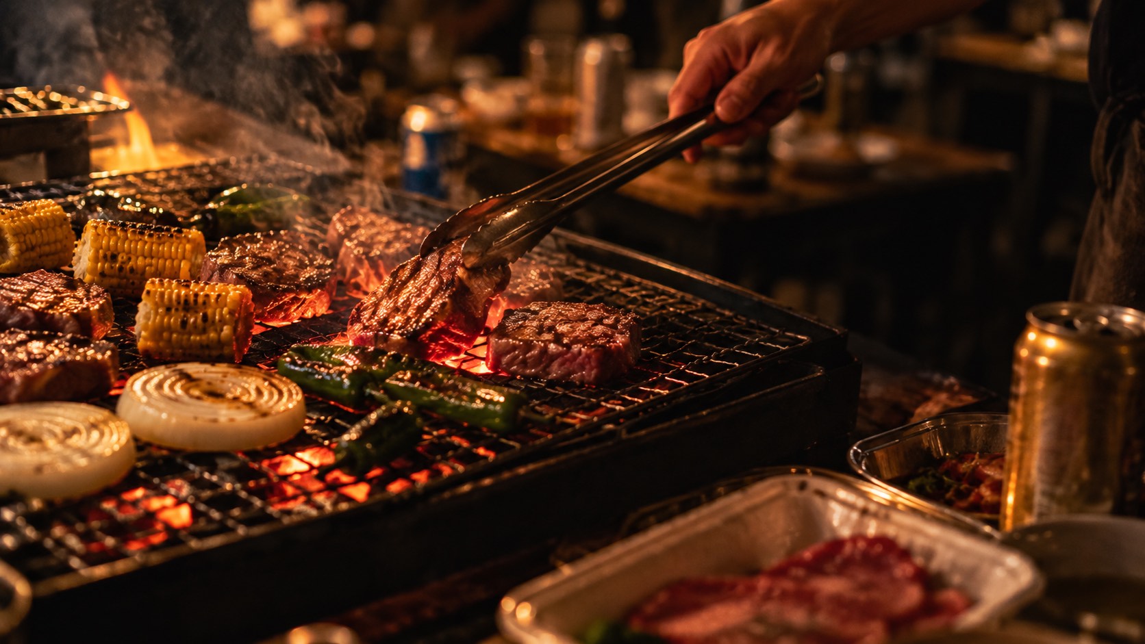 炭火の網の上の肉と野菜。トングで肉を返す手元